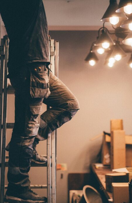Ouvrier sur une échelle dans un intérieur éclairé.